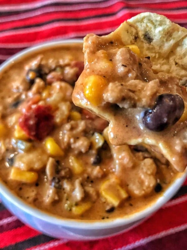 creamy taco high protein soup in a bowl with a baked tortilla chip dipped in it