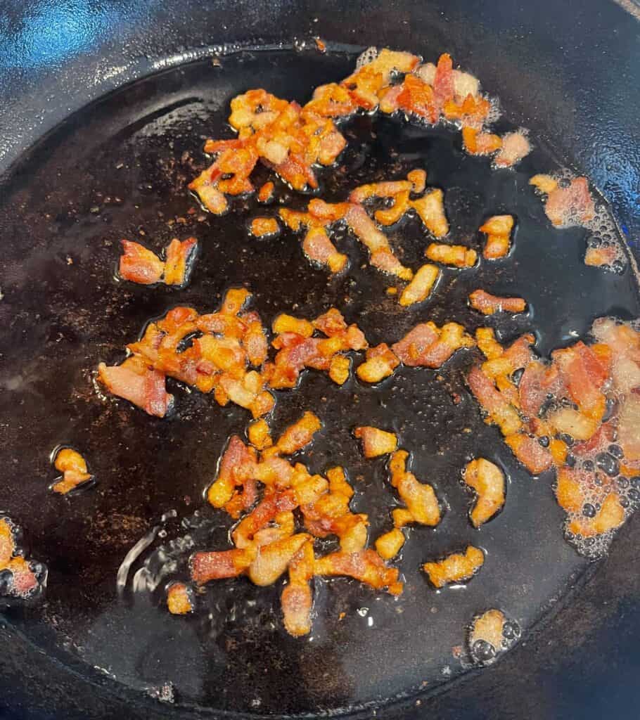 cooking diced bacon in a cast iron skillet