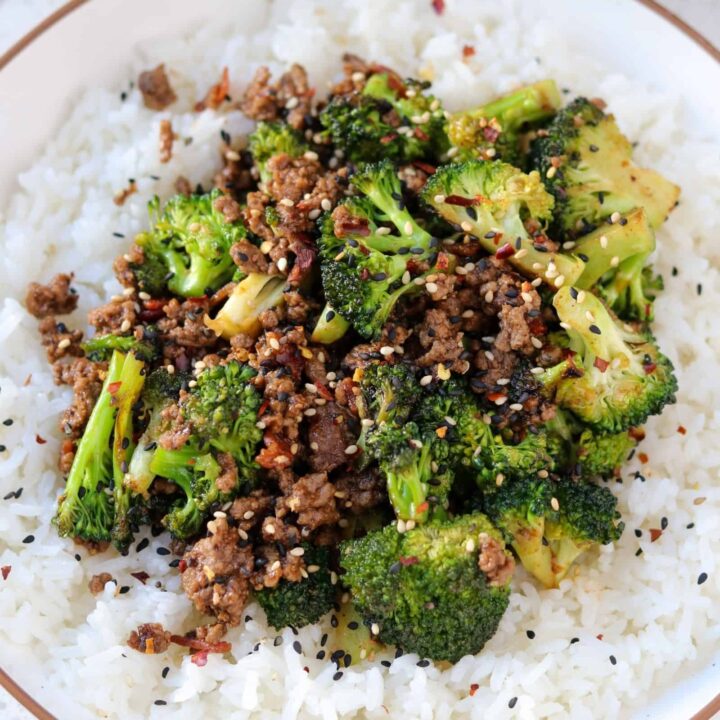 ground beef and broccoli on top of rice garnished with sesame seeds and chili flakes