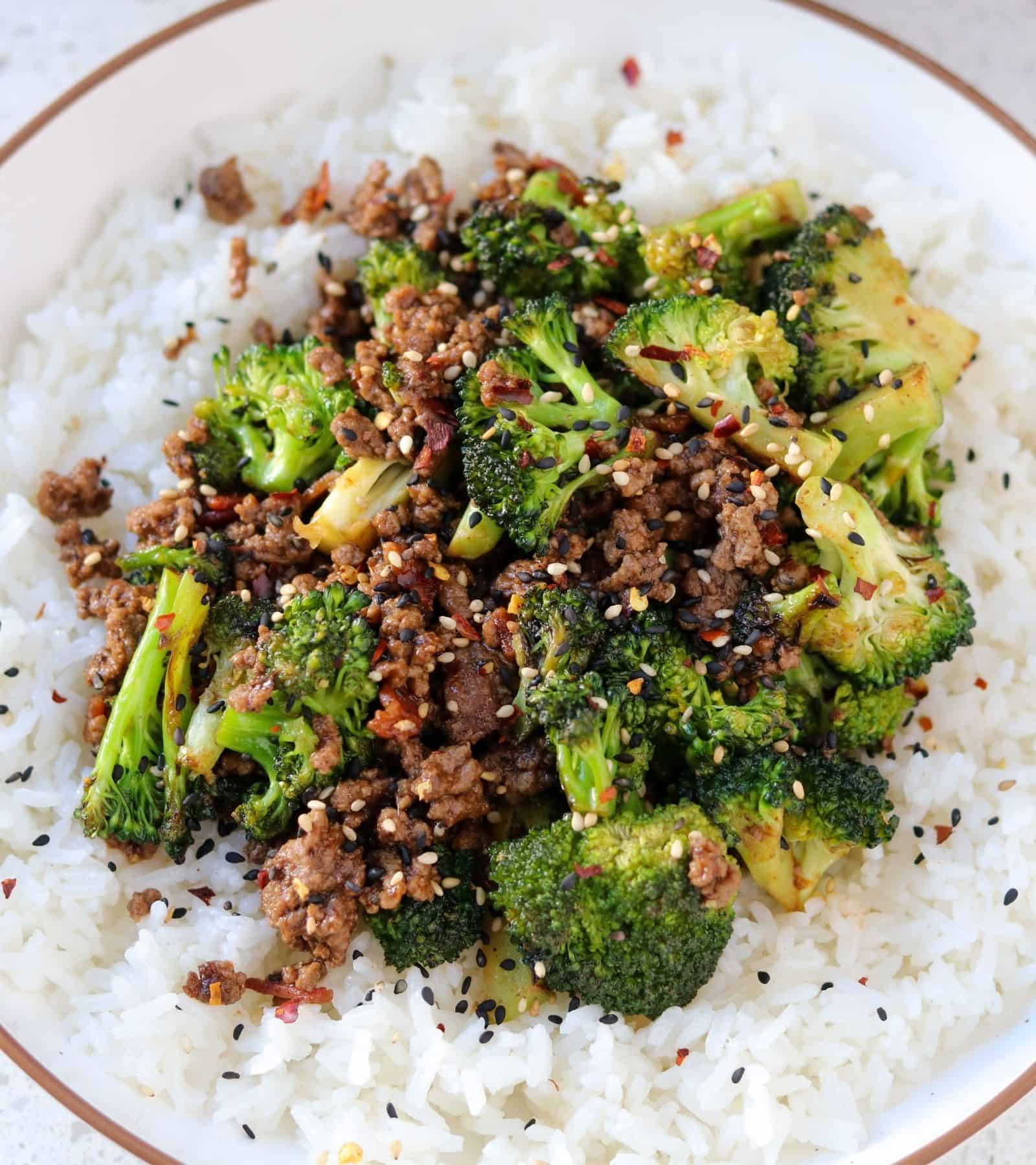 ground beef and broccoli on top of rice garnished with sesame seeds and chili flakes