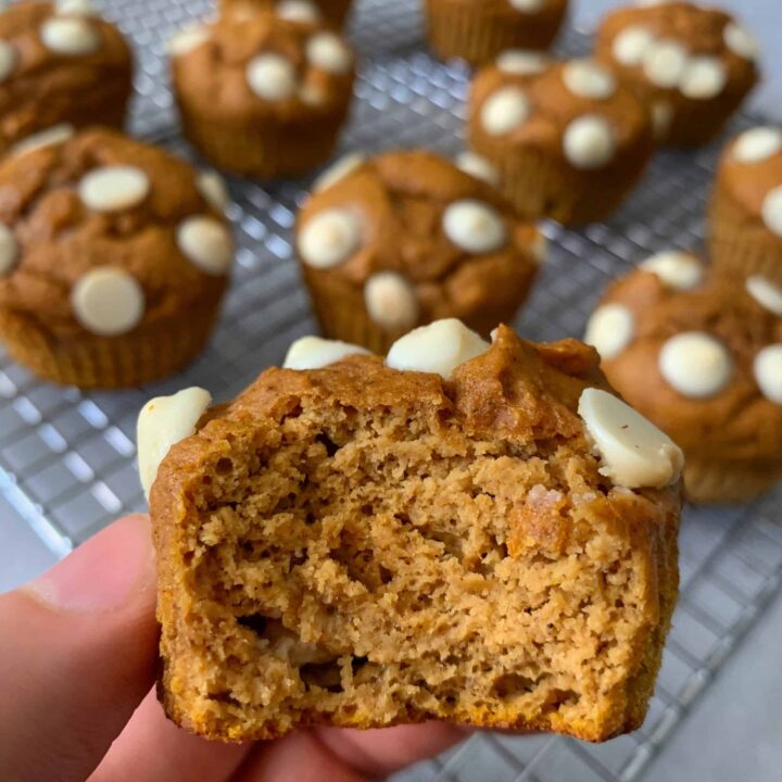 fingers holding a white chocolate pumpkin protein muffins