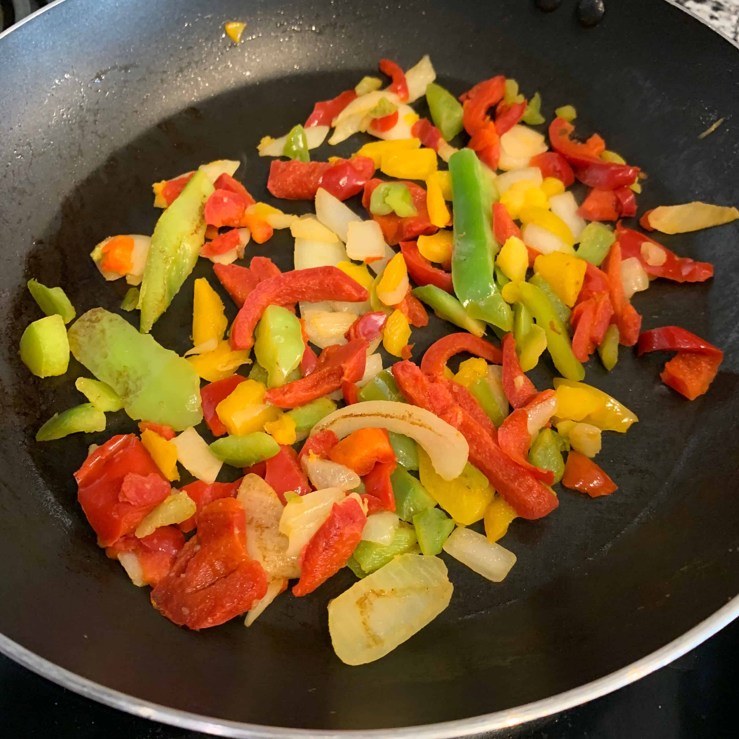 onions and peppers in the skillet for breakfast nachos