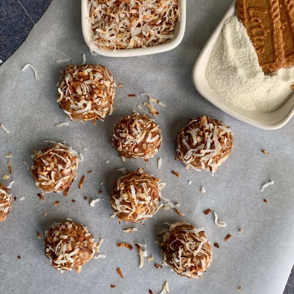 cookie butter protein balls beside a bowl of toasted coconut