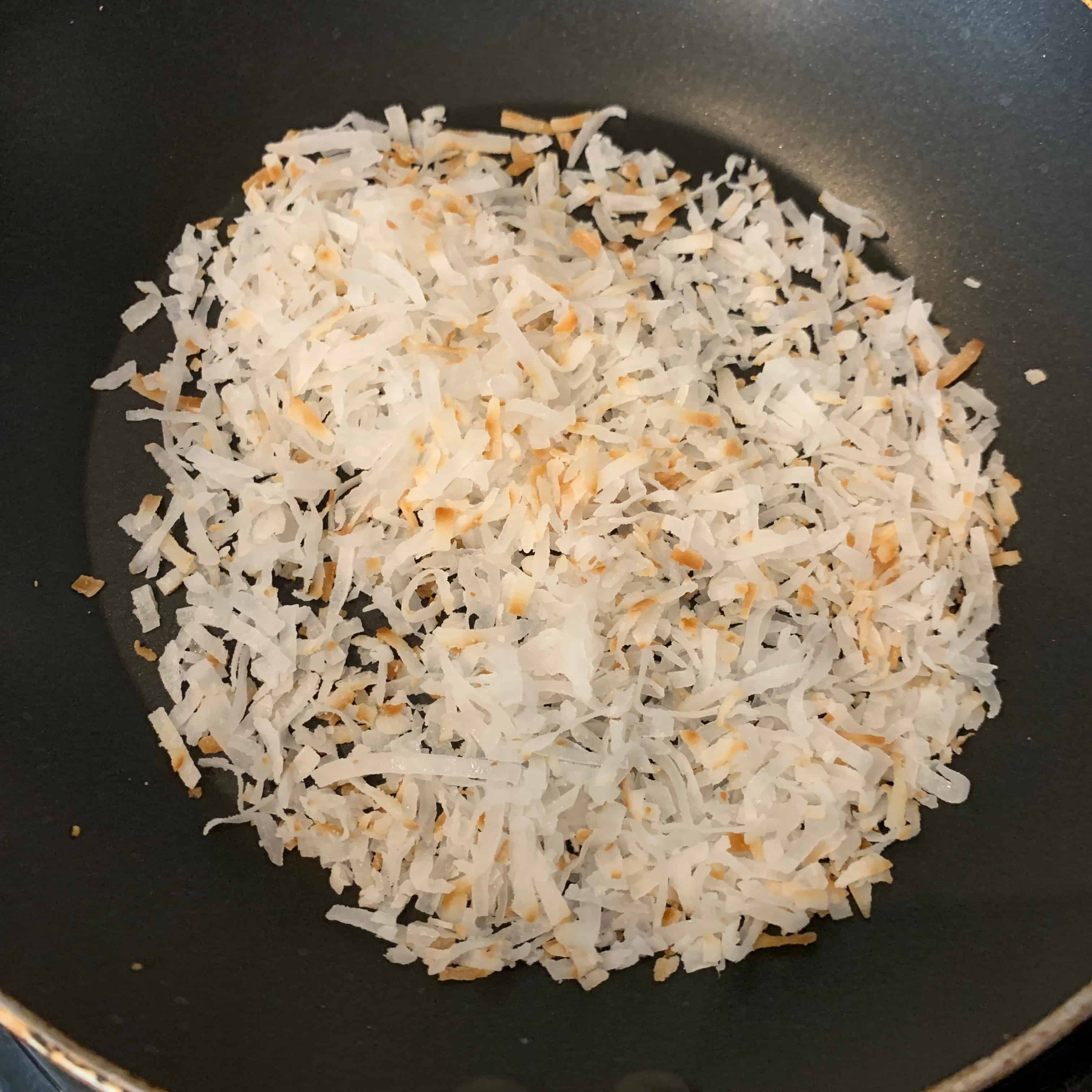 toasting sweetened coconut flakes in a pan