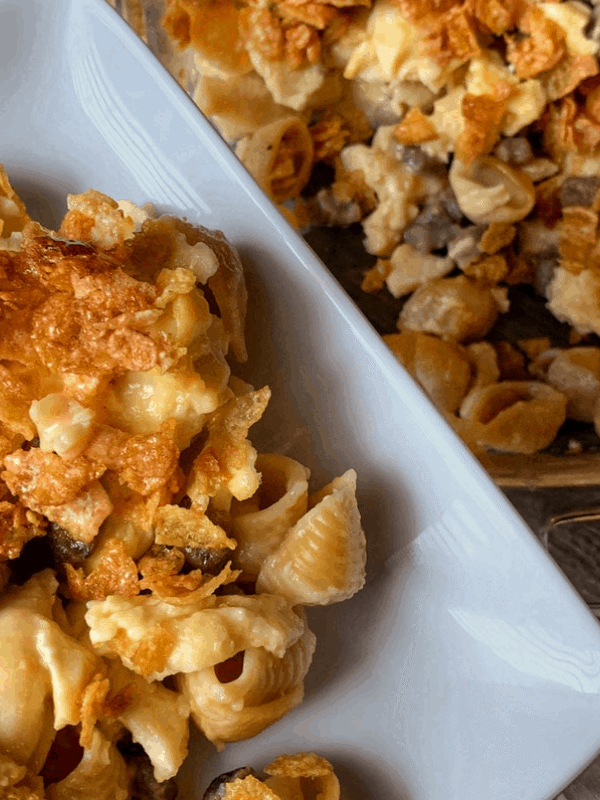 one serving of the breakfast mac and cheese on a plate overlooking the baking dish of mac and cheese