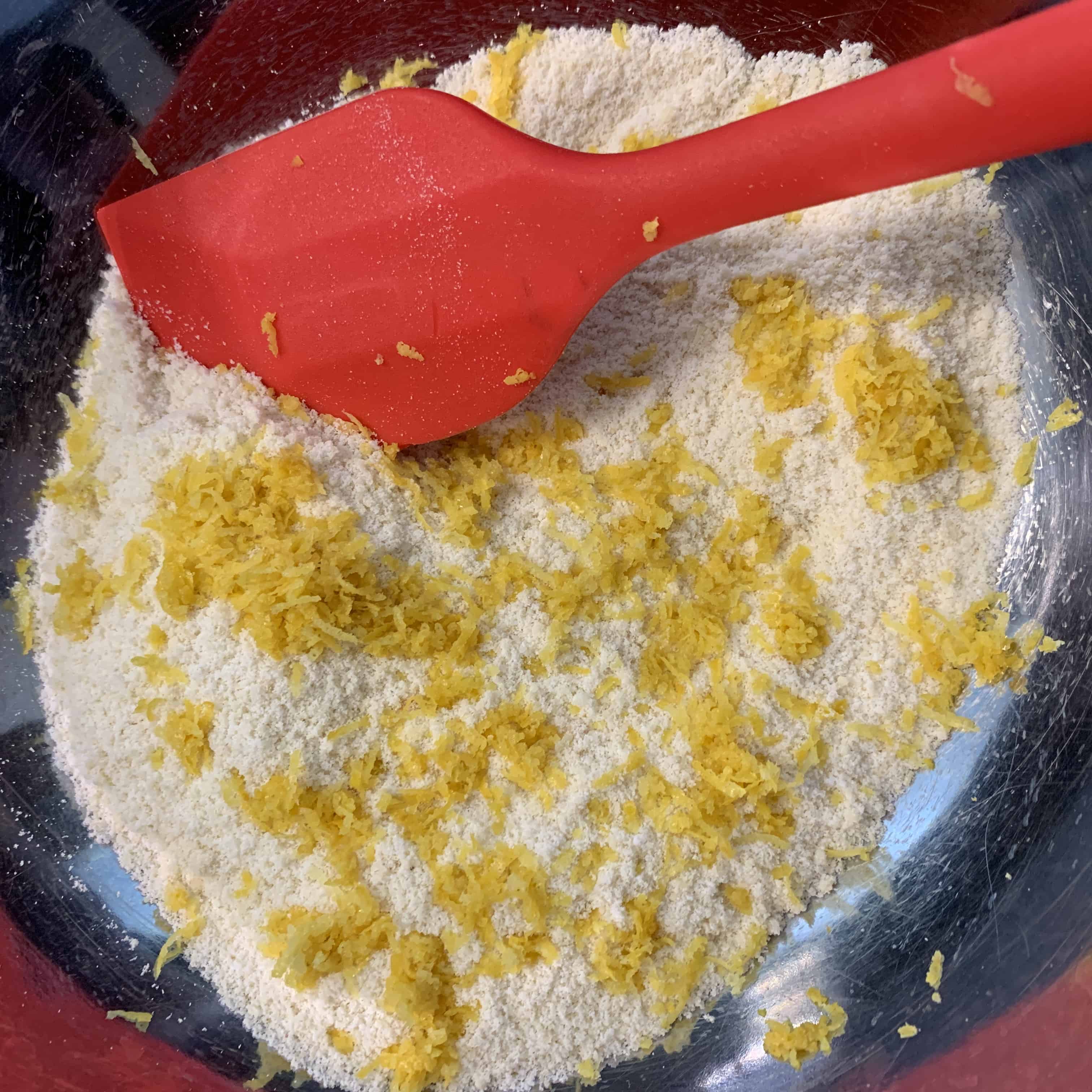 dry ingredients for lemon protein cookies mixed in a bowl with lemon zest on top