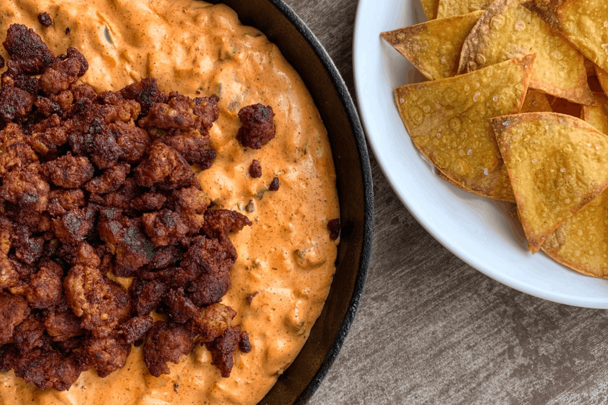 chorizo dip in a skillet with tortilla chips on a white plate