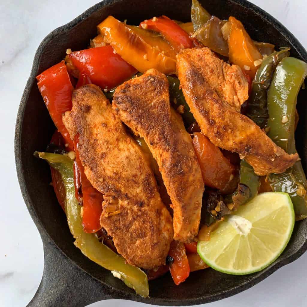 fajita chicken and peppers in a cast iron skillet