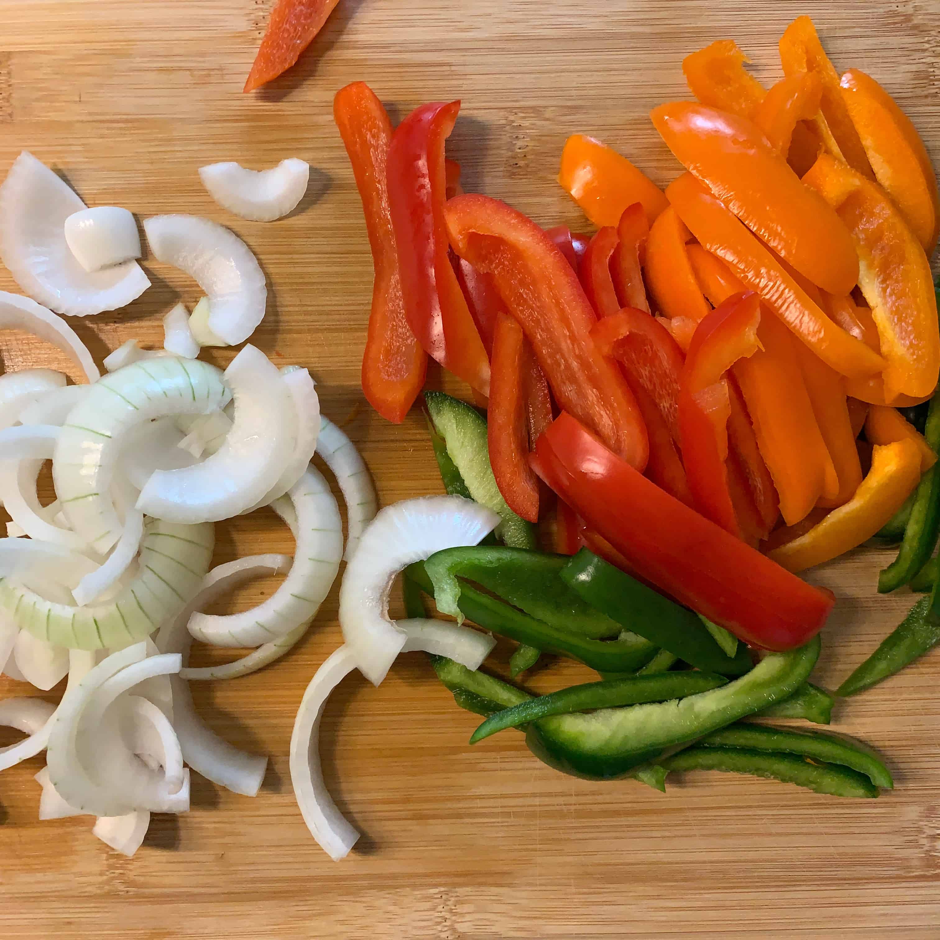 sliced peppers and onion on a cutting board