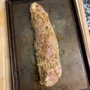 pork tenderloin on a baking sheet with the remaining dry spices rubbed on top