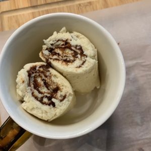 two cinnamon rolls in a mug before microwaving