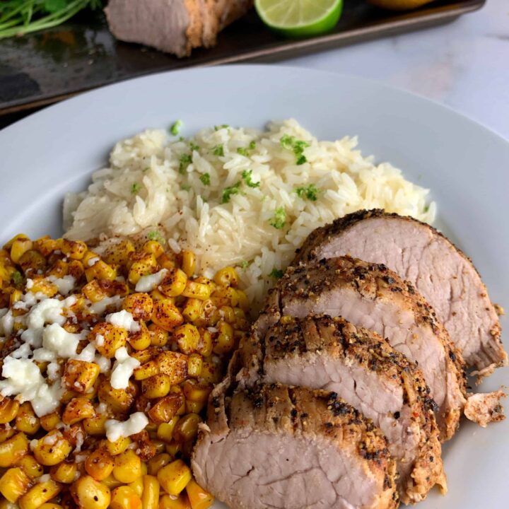 slices of the baked pork tenderloin with a side of corn and rice