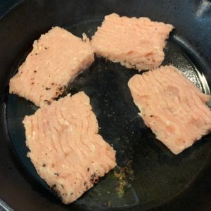 ground chicken pieces spice side down in a cast iron skillet