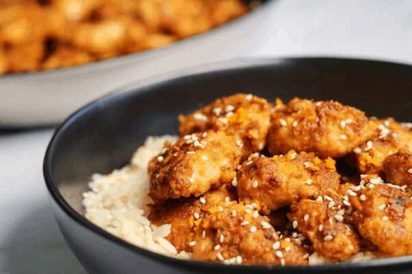 healthy baked orange chicken in a black bowl