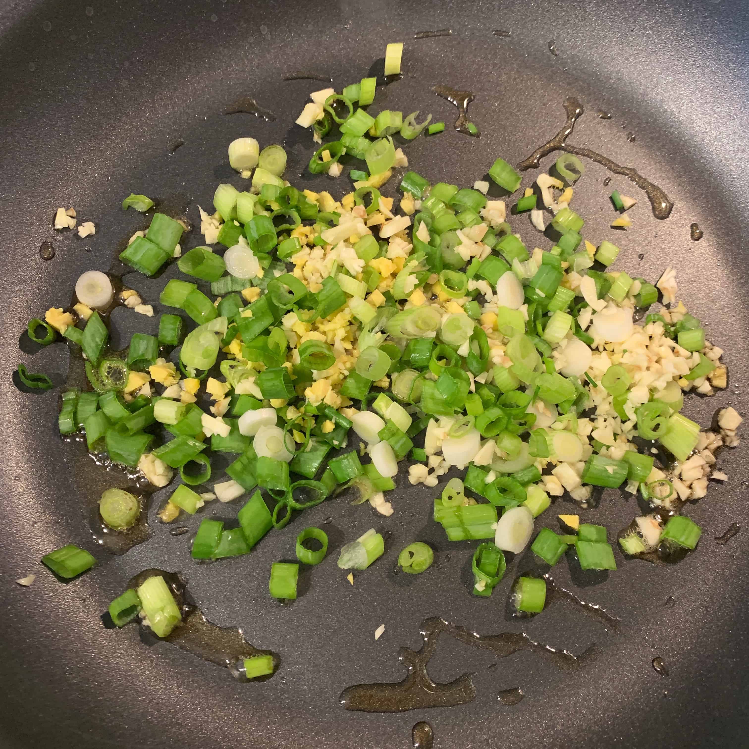scallions, ginger, and garlic in a skillet with sesame oil
