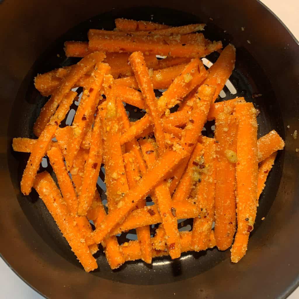 carrot fries in an air fryer basket before frying