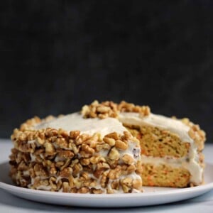 carrot protein cake with cream cheese frosting on a white plate with a slice cut out