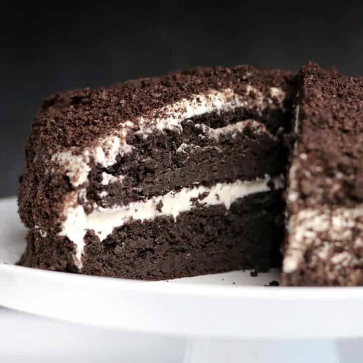 oreo protein cake with a slice cut out sitting on a white serving dish