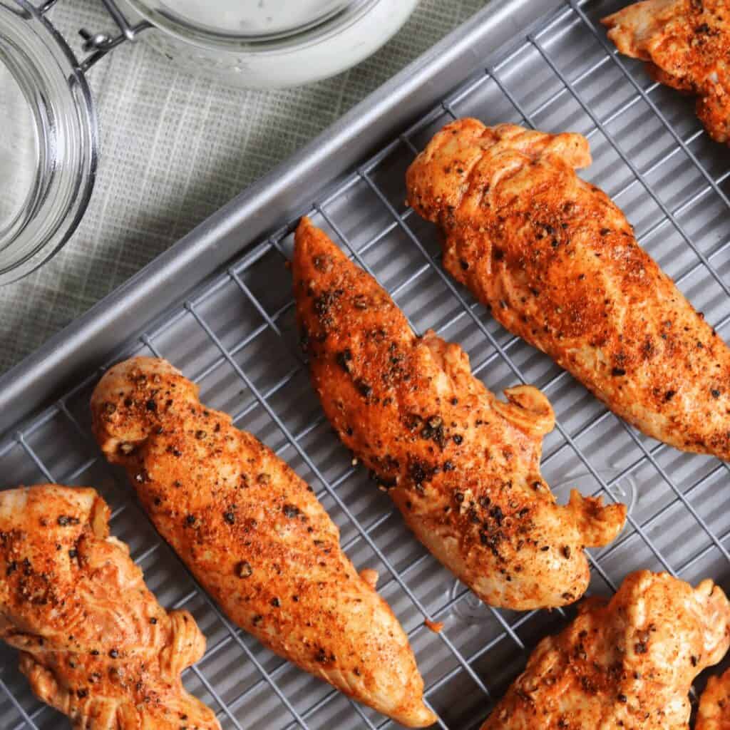 spicy baked chicken tenderloins on a wire rack with low fat ranch dipping sauce