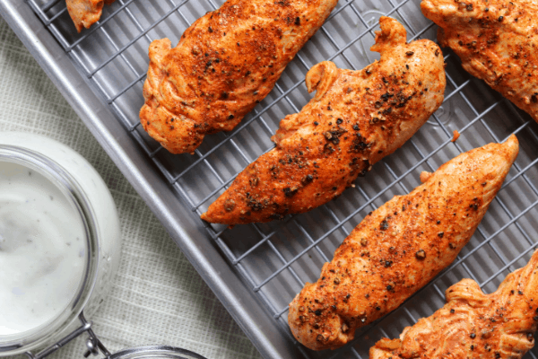 chicken tenderloins on a baking sheet beside Greek yogurt ranch dip