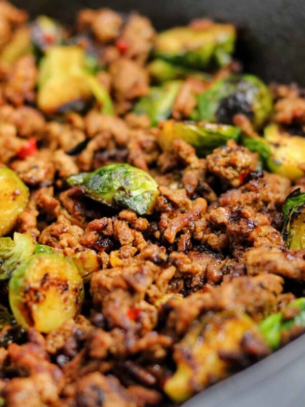 ground beef and brussels sprouts in a cast iron skillet with sweet chili sauce