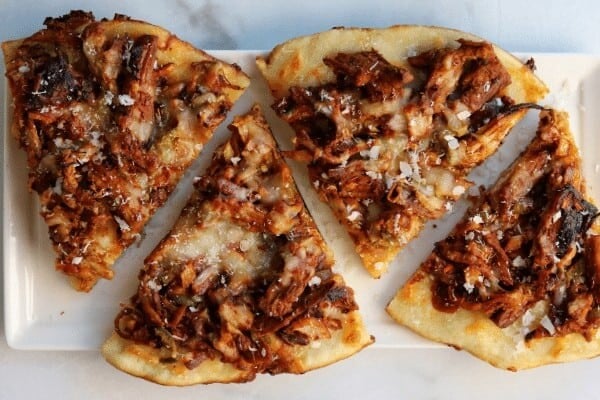 slices of pulled pork pizza on a white plate
