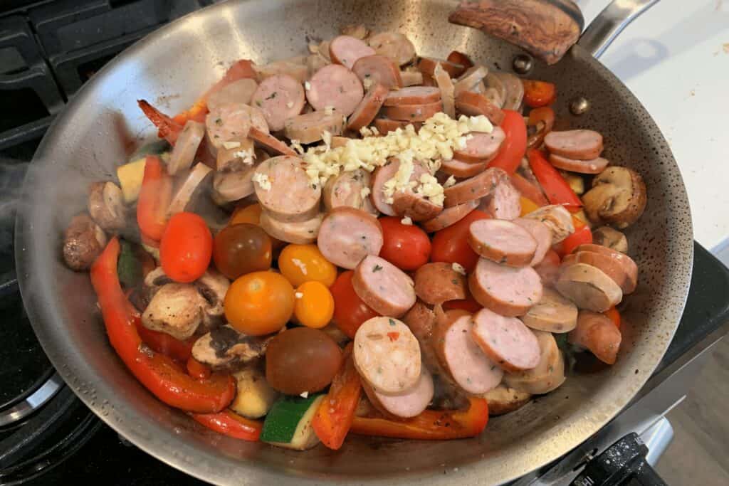 cherry tomatoes, minced garlic, and sliced chicken sausage added to the mushroom and pepper mixture