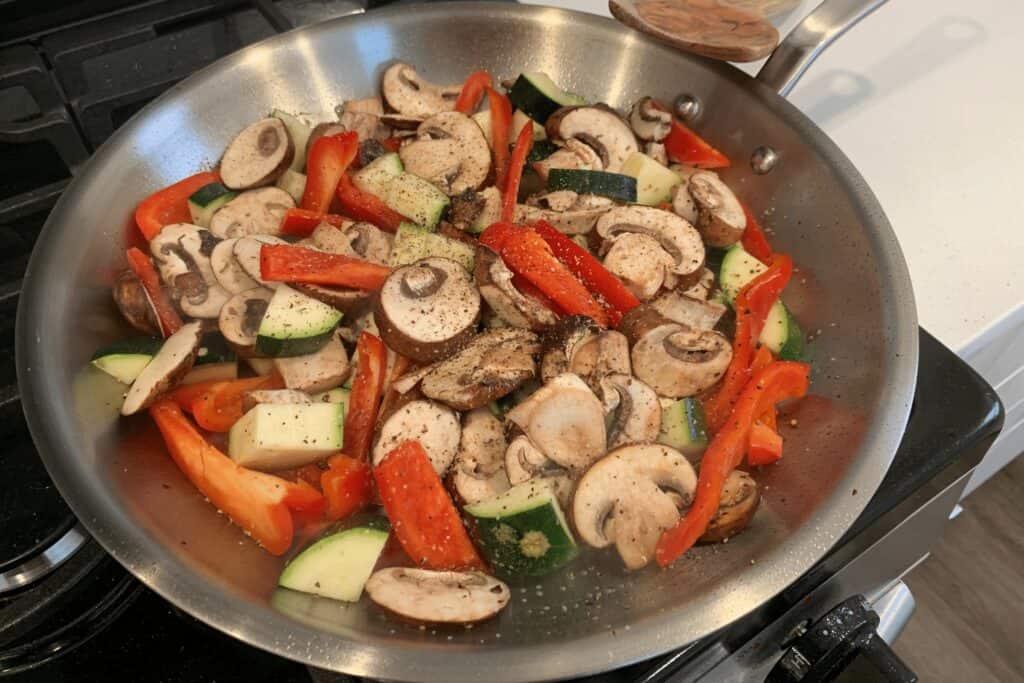 sliced baby bella mushrooms, red bell pepper, and zucchini in a skillet with olive oil, salt, and black pepper