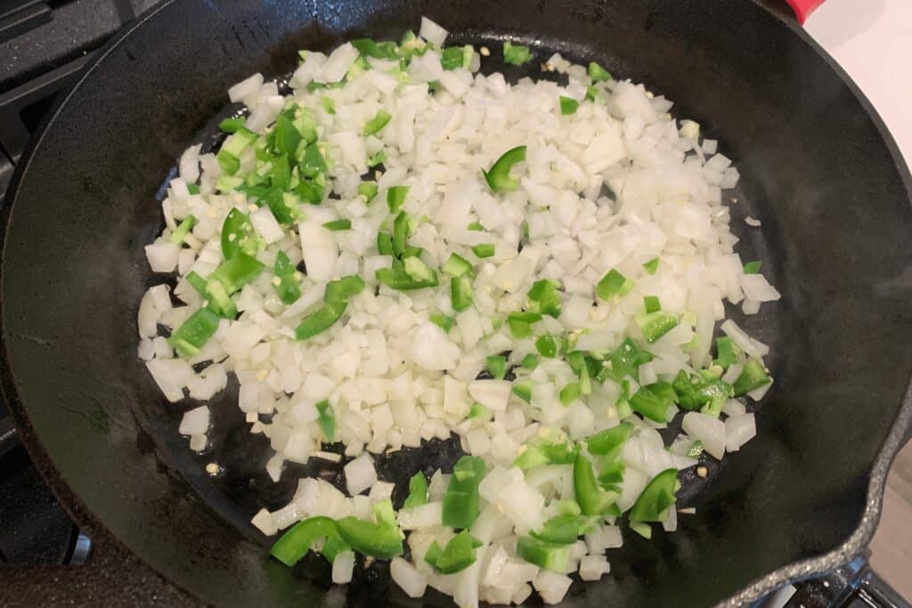 diced onion and jalapeño in a cast iron skillet with olive oil