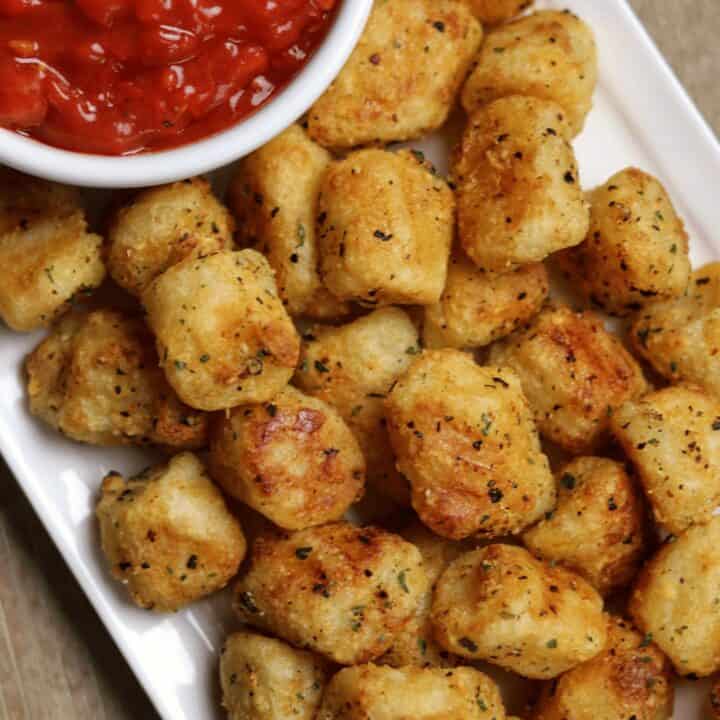 air fred cauliflower gnocchi on a white plate with a bowl of spicy ketchup