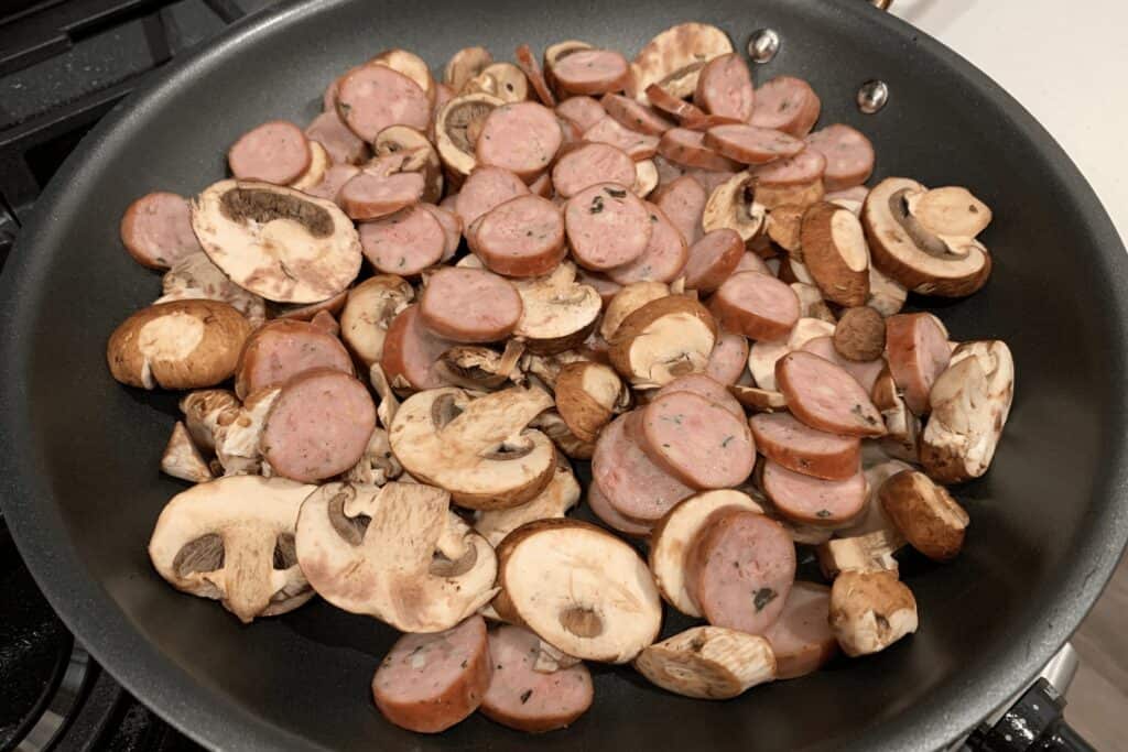 sliced chicken sausage and mushrooms in a pan