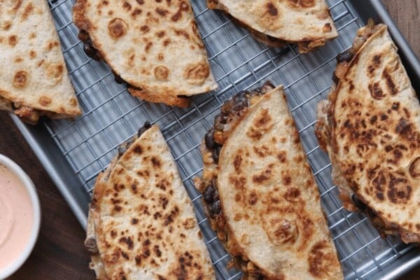 black bean and corn quesadillas on a baking sheet with Greek yogurt dip