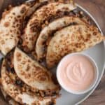 cheesy black bean and corn quesadillas on a plate with Greek yogurt dipping sauce