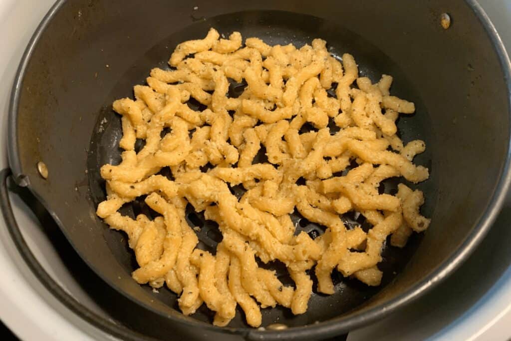 coated pasta in the air fryer basket before air frying