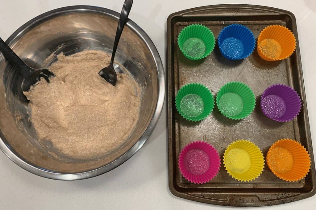 mixed protein muffin batter and 9 silicone muffin molds on a baking sheet