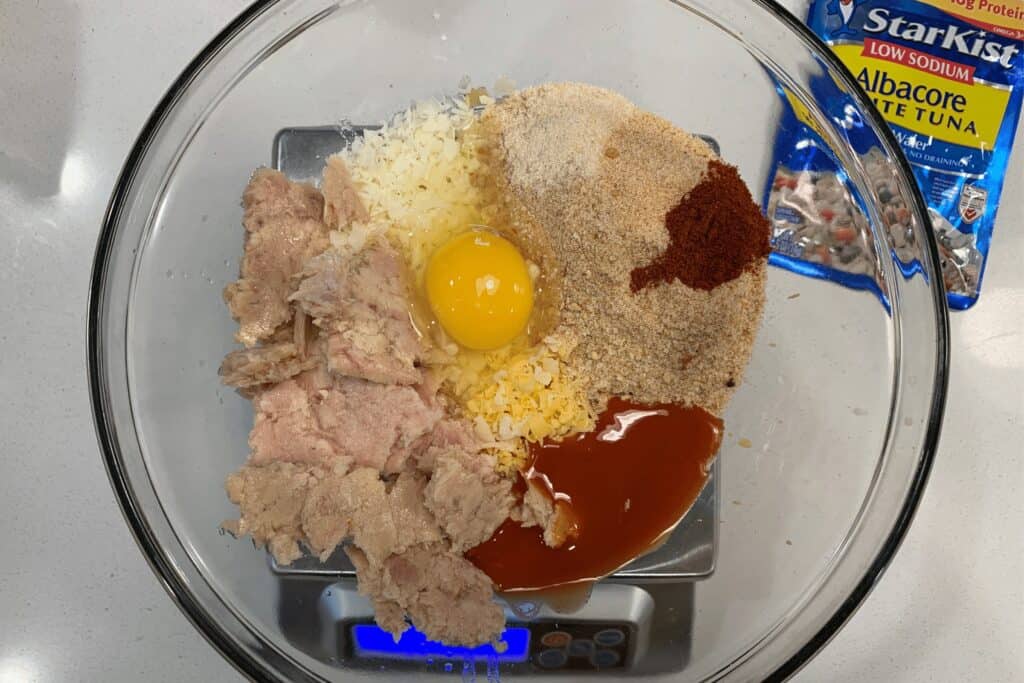 tuna, breadcrumbs, parmesan, cheddar, buffalo sauce, spices, and an egg in a mixing bowl