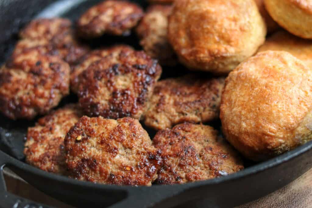 chicken breakfast sausage patties in a skillet with biscuits