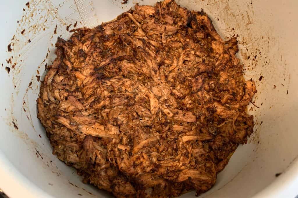 shredded jerk pork tenderloin back in the Ninja Foodi pot after broiling