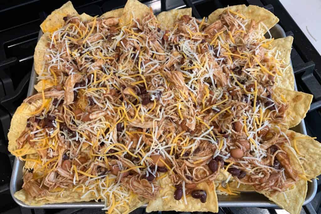 tortilla chips with buffalo chicken and shredded cheese before baking