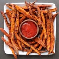sweet potato fries on a white plate with ketchup