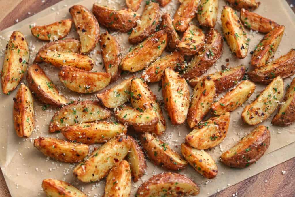 garlic parmesan air fryer red potatoes on parchment paper with grated parmesan and parsley flakes