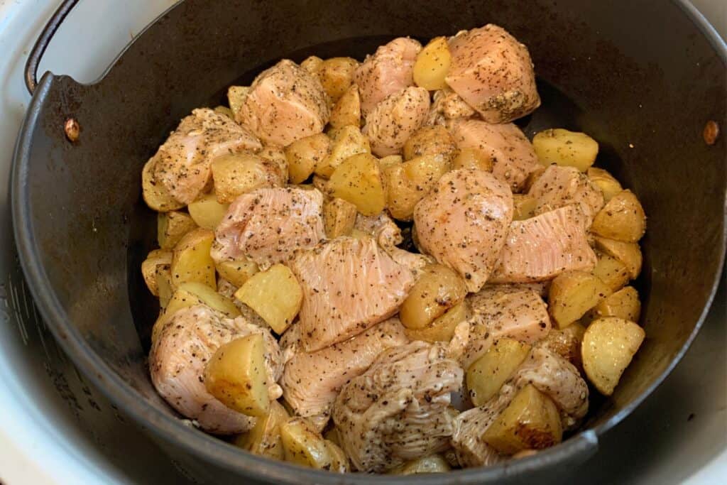 seasoned Greek chicken and potatoes in the air fryer basket