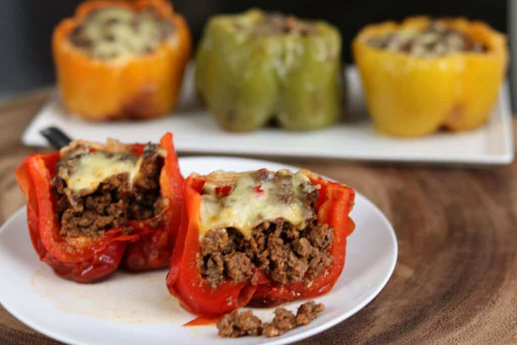 stuffed pepper cut in half on a white plate with 3 stuffed peppers in the background