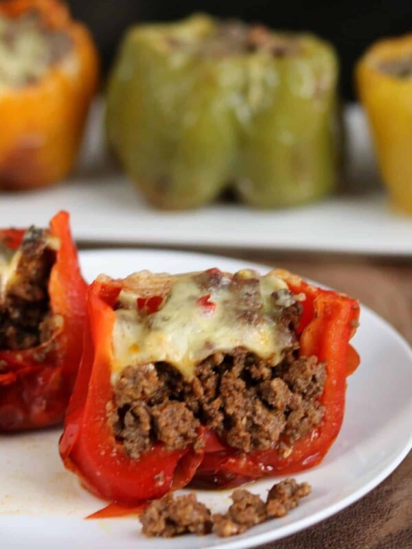 stuffed pepper cut in half on a white plate with 3 stuffed peppers in the background