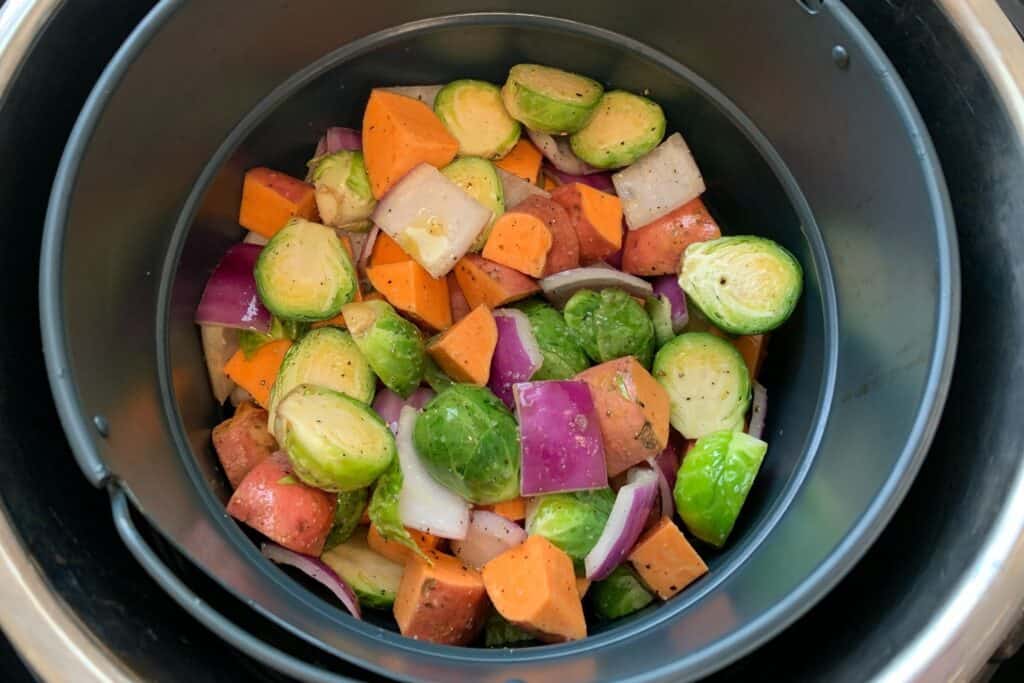 brussels sprouts, sweet potatoes, and red onion in an air fryer basket