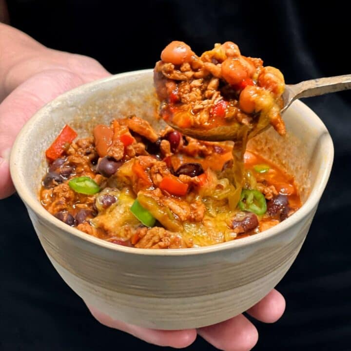 holding a bowl of turkey chili with melted cheddar