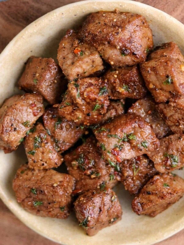 air fried steak bites in a bowl topped with garlic butter