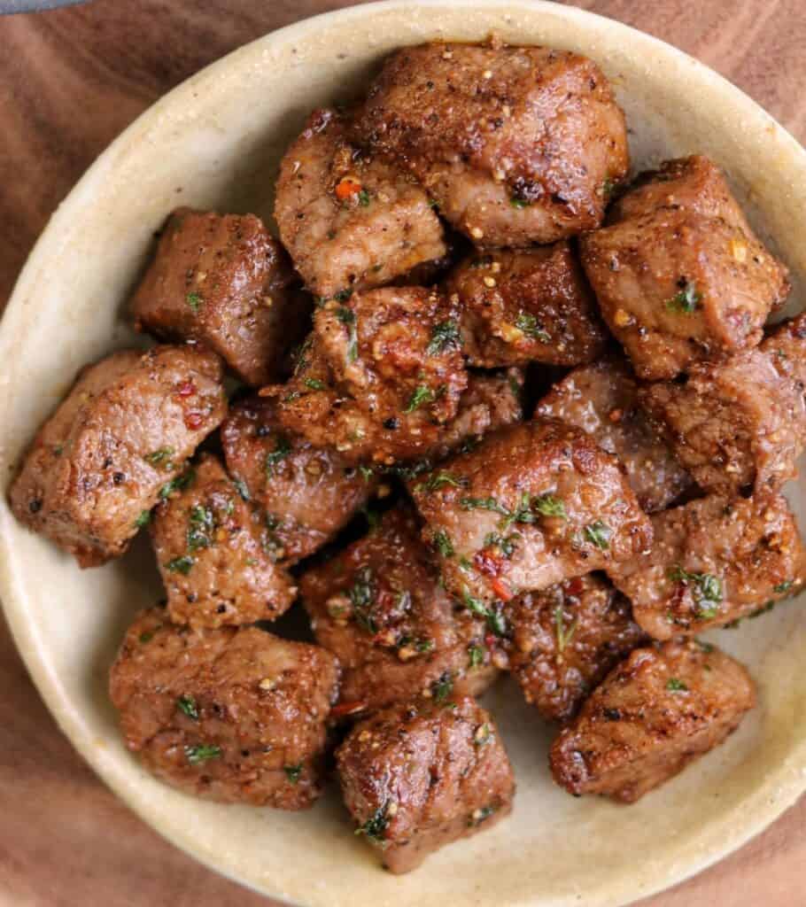 air fried steak bites in a bowl topped with garlic butter