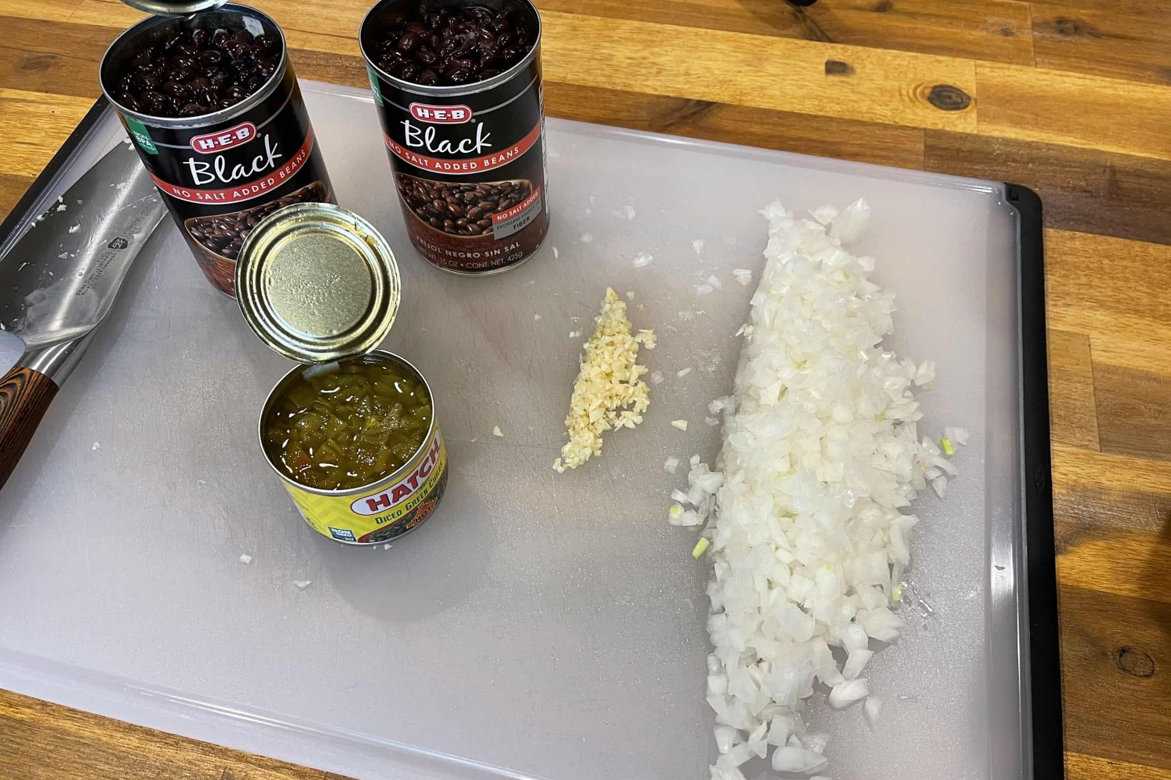 adding hot sauce and diced green chiles to the cooked onion and garlic