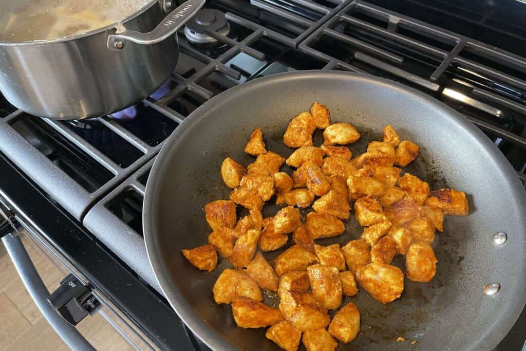 cooking chicken breast in a skillet and boiling water for pasta
